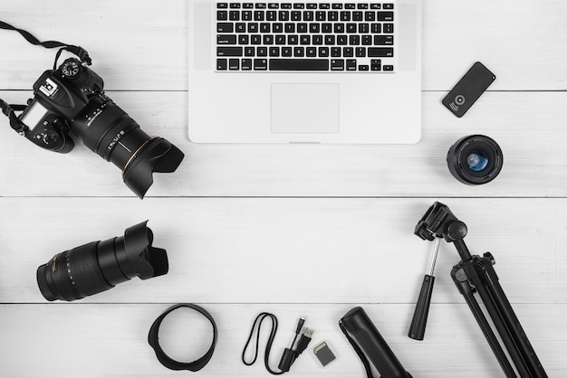 Computer portatile circondato con accessori della fotocamera sullo scrittorio di legno bianco Foto Gratuite