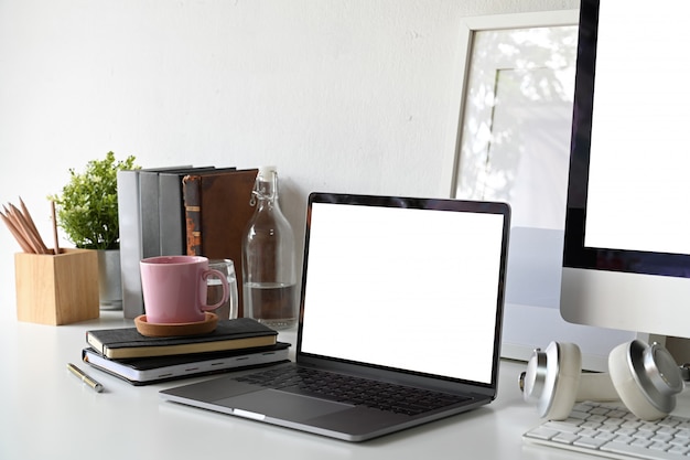 Computer portatile dello schermo in bianco con il manifesto e le forniture per ufficio in bianco. Foto Premium