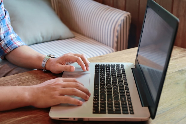 Computer portatile di battitura a macchina dello schermo e dell'uomo commovente delle donne sulla tavola di legno Foto Premium