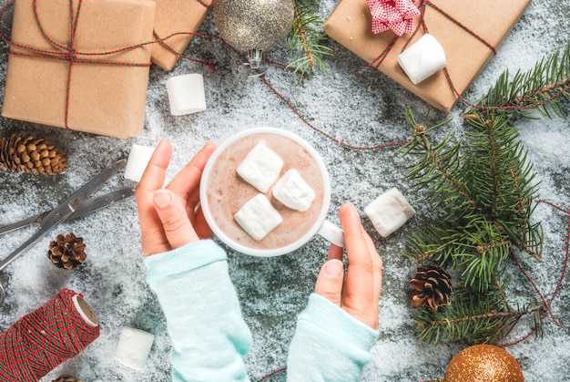 Albero Di Natale Con Pigne E Neve.Concetto Di Natale Sfondo Del Tavolo Con Neve Rami Di Alberi Di Natale Ragazza Tiene Una Tazza Di Cioccolata Calda Con Marshmallow Regali O Regali Pigne E Decorazioni Foto Premium