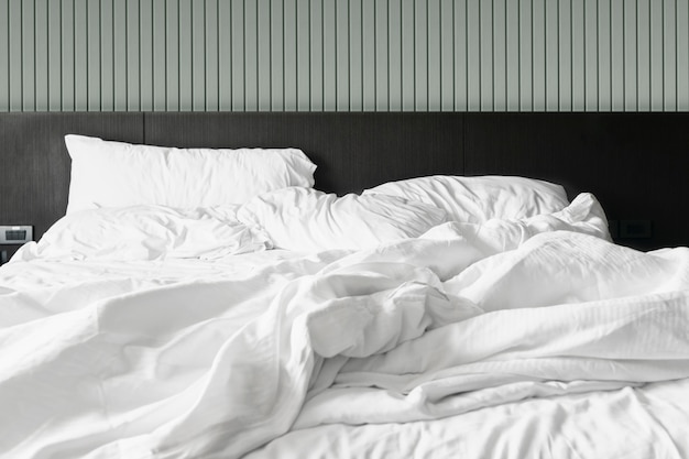 Confortevole camera da letto lenzuola bianche disordinate e piumone disordinato in camera da letto Foto Premium