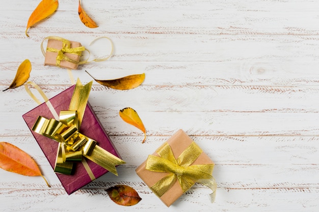 Contenitori di regalo in carta da imballaggio con i nastri e le foglie di autunno su un fondo di legno bianco Foto Gratuite