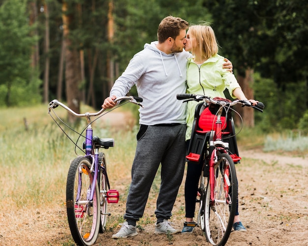 Coppia baciarsi accanto a biciclette sul sentiero forestale Foto Gratuite