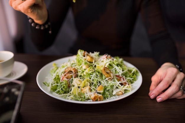 Deliziosa insalata con crostini di pane; gamberi e parmigiano grattugiato sul tavolo di fronte a una persona Foto Gratuite