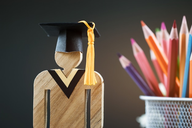 Di nuovo al concetto della scuola, la gente firma il legno con la scatola della matita della sfuocatura del cappuccio di celebrazione di graduazione Foto Premium