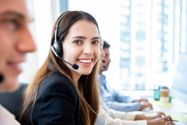 Donna amichevole sorridente che lavora nell'ufficio di call center con la squadra Foto Premium