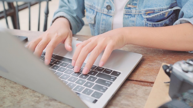 Donna asiatica indipendente di affari che lavora, facendo progetti e inviando email sul computer portatile o sul computer mentre sedendosi sulla tavola in caffè. belle donne astute di stile di vita che lavorano ai concetti della caffetteria. Foto Gratuite