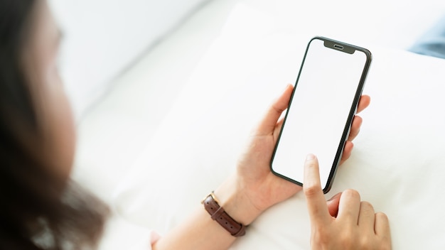 Donna che utilizza lo schermo in bianco dello smartphone sulla stanza, durante il tempo libero. Foto Premium
