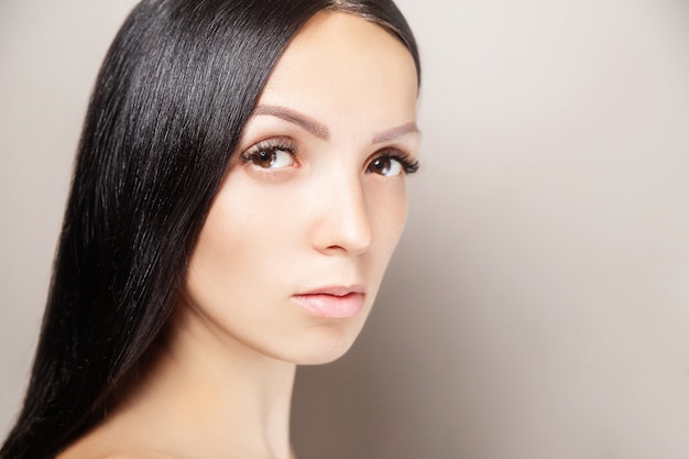 Donna con i capelli scuri lucenti e lunghe ciglia marroni. ritratto di bellezza femminile estensioni delle ciglia, cura della pelle, concetto di bellezza e spa Foto Premium