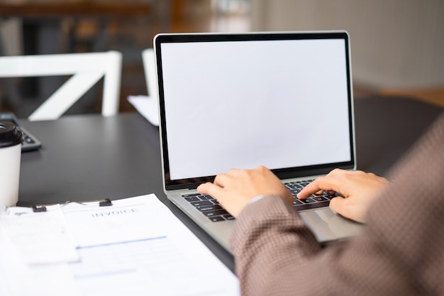 Donna di affari che usando e che scrive sul computer portatile bianco dello schermo del modello nel suo ufficio. Foto Premium