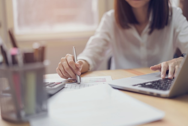 Donna di affari in ufficio e utilizzare computer e calcolatrice per eseguire la contabilità finanziaria. Foto Premium