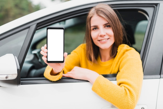 Donna in automobile che mostra lo schermo del telefono Foto Gratuite