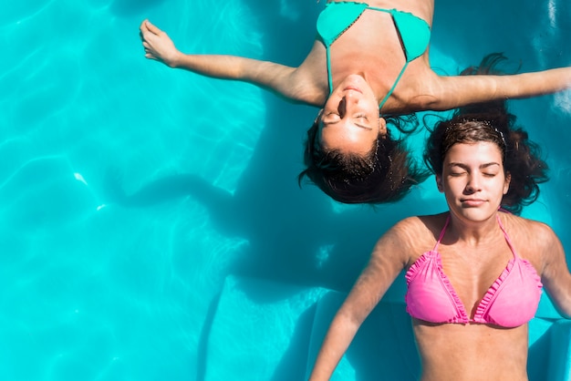 Donne adulte con gli occhi chiusi, rilassarsi in piscina Foto Gratuite