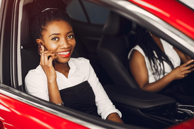 Due donne di colore alla moda in un salone di auto Foto Gratuite