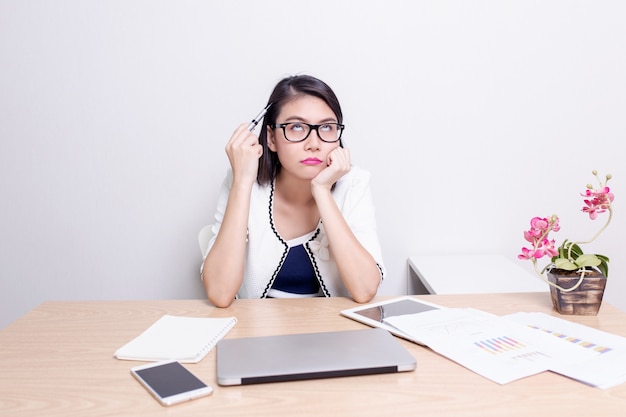 Esecutivo femminile asiatico serio che trova le idee mentre lavorando al suo scrittorio con il computer portatile Foto Premium