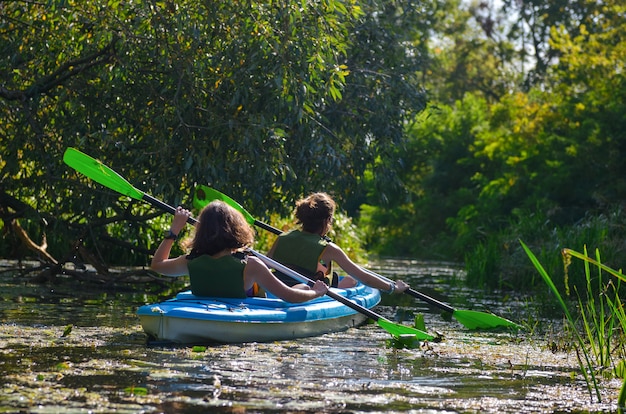 Famiglia kayak, madre e figlia pagaiando in kayak sul tour in canoa sul fiume divertendosi, weekend autunnale attivo e vacanze con i bambini, concetto di fitness Foto Premium