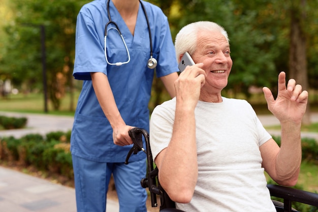Felice vecchio in sedia a rotelle a parlare su un telefono cellulare Foto Premium