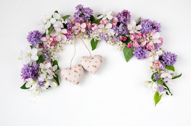 Fiori del ciliegio degli uccelli, lillà e meli foderati con un arco e due cuori di tessuto Foto Premium