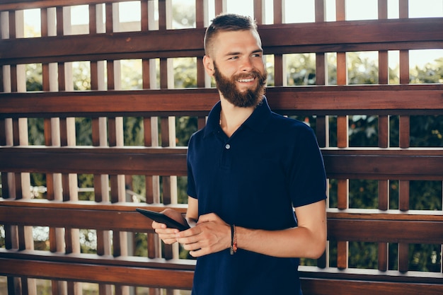 Giovane ragazzo con la barba lavora in un bar, un libero professionista usa un tablet, fa un progetto Foto Gratuite