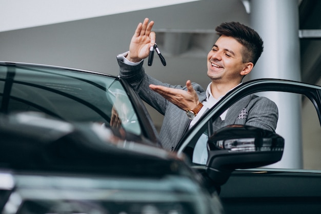Giovane uomo bello di affari che sceglie un'automobile in una sala d'esposizione dell'automobile Foto Gratuite