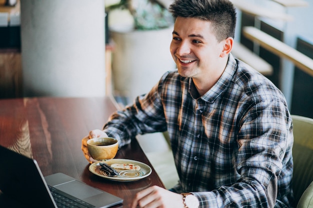 Giovane uomo bello di affari che utilizza computer portatile in un caffè Foto Gratuite