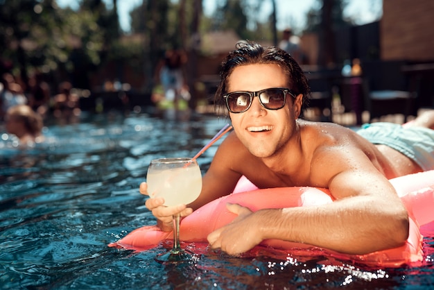 Giovane uomo sorridente in occhiali da sole sul materasso ad aria Foto Premium