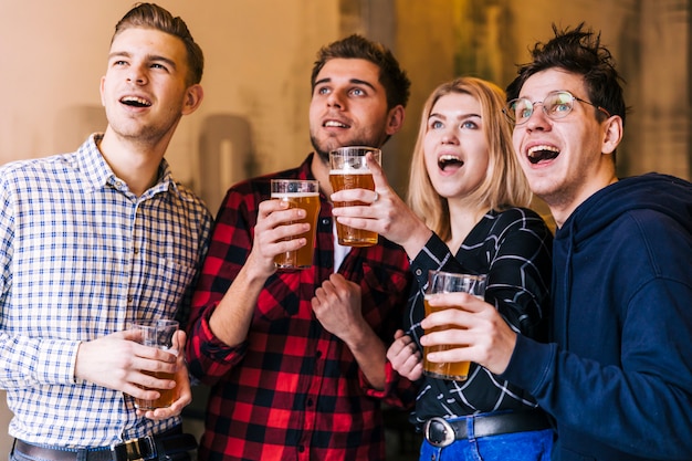 Giovani amici eccitati godendo la birra mentre si guarda qualcosa Foto Gratuite