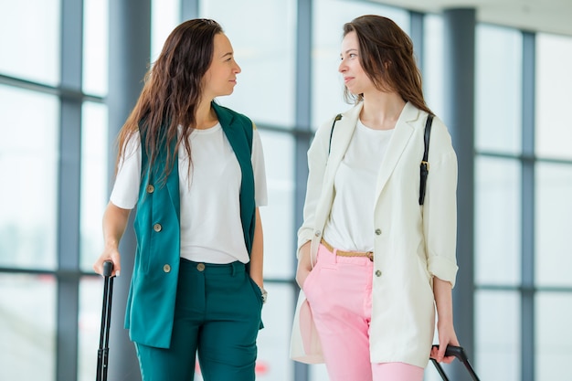 Giovani donne con bagaglio in aeroporto internazionale a piedi con i suoi bagagli. i passeggeri delle compagnie aeree in un aeroporto lounge in attesa di volo aereo Foto Premium