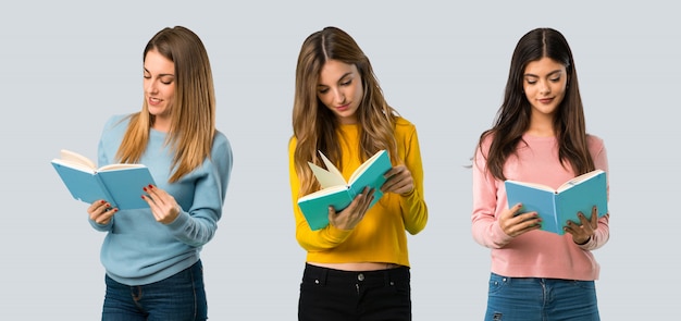 Gruppo di persone con abiti colorati in possesso di un libro e godendo la lettura sul retro colorato Foto Premium