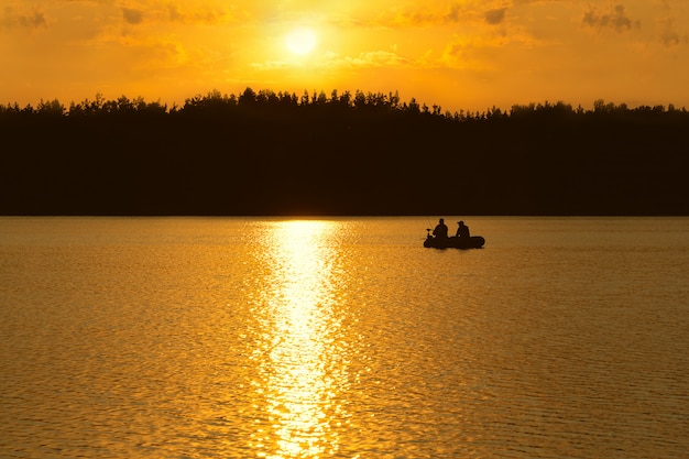 I pescatori pescano sul lago al tramonto. Foto Premium