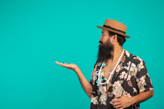 Il di un turista maschio con una lunga barba che indossa un cappello e in possesso di una macchina fotografica su un blu. Foto Gratuite