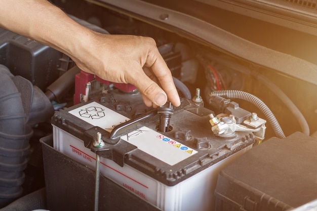 Il funzionamento del meccanico automatico controlla che l'acqua e la batteria del sistema riempiano un vecchio motore di automobile alla stazione di servizio, cambino e riparino prima di guidare Foto Premium