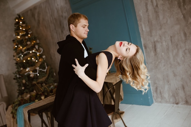 Albero Di Natale Rosso E Nero.Il Ragazzo E La Ragazza Stanno Cenando Al Tavolo Festivo Il Tavolo E Decorato In Stile Capodanno Bionda In Abito Nero Con Rossetto Rosso Sulle Labbra Albero Di Natale Decorato Foto