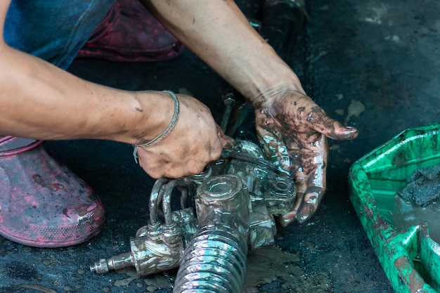 Il riparatore del motore sta usando olio motore per lavare parti del motore. Foto Premium