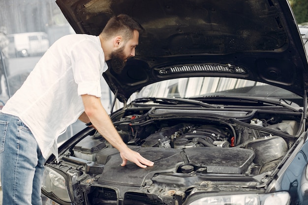 L'uomo bello controlla il motore in sua automobile Foto Gratuite