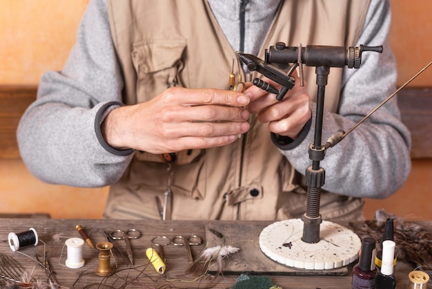 L'uomo che fa la trota vola. attrezzatura per la pesca a mosca e materiale per la preparazione alla pesca a mosca. Foto Premium