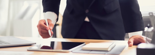 L'uomo d'affari passa la tenuta della penna digitale e la compressa usando con il computer all'ufficio. Foto Premium