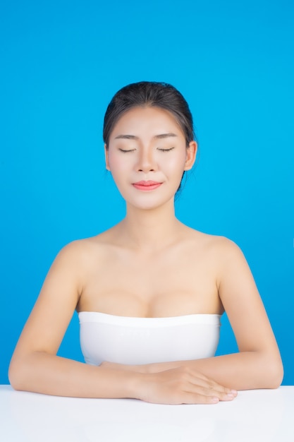 La bellezza delle donne con immagini perfette di salute della pelle toccando il suo viso e sorridendo come una spa per coccolarla. blu Foto Gratuite