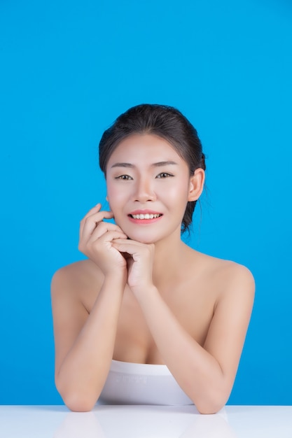 La bellezza delle donne con immagini perfette di salute della pelle toccando il suo viso e sorridendo come una spa per coccolarla. blu Foto Gratuite