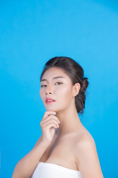 La bellezza delle donne con immagini perfette di salute della pelle toccando il suo viso e sorridendo come una spa per coccolarla. blu Foto Gratuite