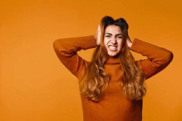 La donna caucasica rossa arrabbiata si è vestita in pullover con le mani sulla sua testa Foto Gratuite