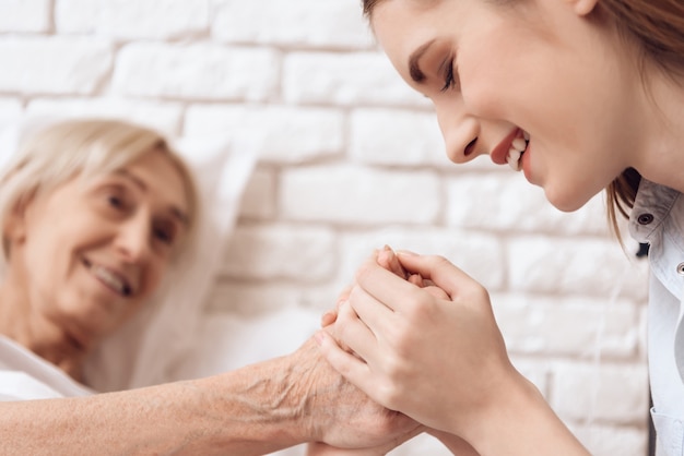 La ragazza sta allattando la donna anziana a casa. Foto Premium