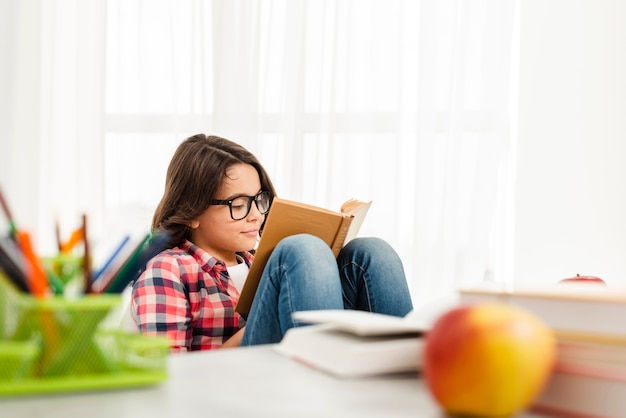 Lettura della ragazza dell'angolo alto a casa Foto Gratuite