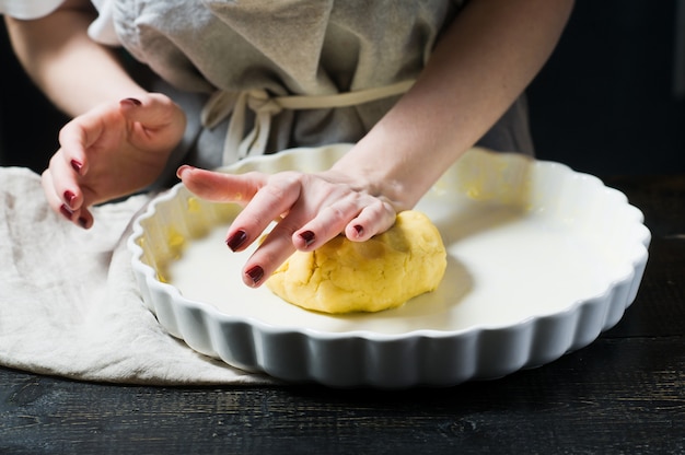 Lo chef stende l'impasto in una pirofila, cucinando. vista laterale Foto Premium