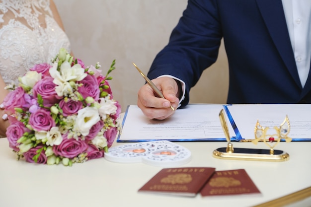 Lo sposo in un giorno del matrimonio mette una firma. cerimonia matrimoniale. Foto Premium