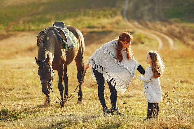 Madre e figlia in un campo che gioca con un cavallo Foto Gratuite