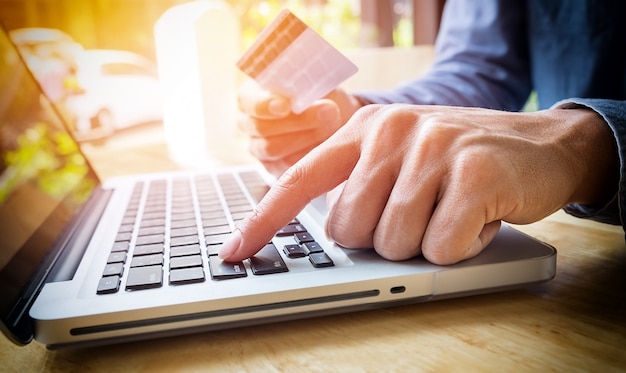 Man holding carta di credito in mano e l'immissione di codice di sicurezza utilizzando la tastiera del computer portatile Foto Gratuite