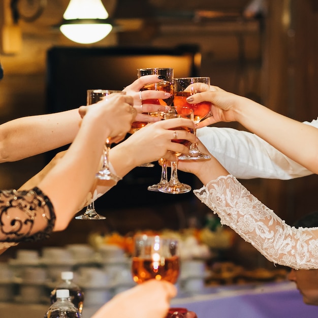 Mani di un gruppo di persone che tintinnano e tostano bicchieri di vino rosso a una festa in un ristorante Foto Premium