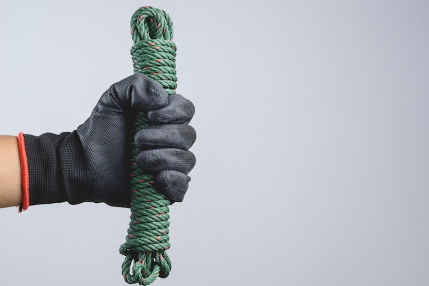 Mano che indossa un guanto scuro e tiene in mano un cavo verde per paracadute di corda di nylon Foto Premium