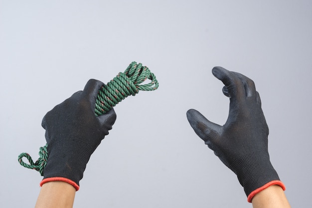 Mano che indossa un guanto scuro e tiene in mano un cavo verde per paracadute di corda di nylon Foto Premium